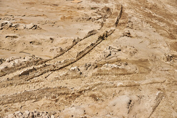 Traces of tread construction equipment on the sand.