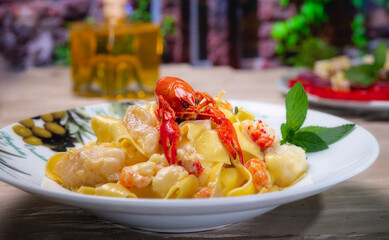 Italian national cuisine, pappardelle with pieces of cod and crayfish. In rustic style. Unusual background. Beautiful ceramic tableware.