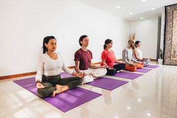 Yogi people practicing yoga lesson. Breathing and meditation in Lotus pose in group. Close up of hands. Well being, wellness concept. Indoors Workout in studio.