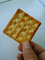 hand holding a cracker biscuit sprinkled with granulated sugar