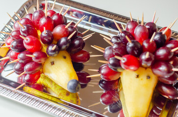 Two fruit shaped like hedgehogs are on a silver tray