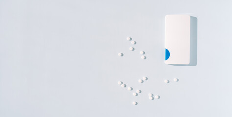 Scattered sweeteners in the form of tablets next to packaging on a blue background.