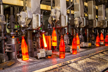 Glass factory, production of glass containers. Molten glass is blown into molds. Robotics in industry. Modern technologies, robotic machines produce products. Technological work at the plant.