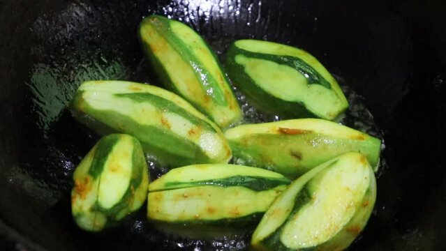 Close-up video of pointed gourd, parwal, parval (patol) frying in pan.4k. Pointed gourd potato curry, Indian food. 
