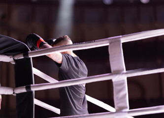 A man is boxing in a ring with a white and black striped fence 