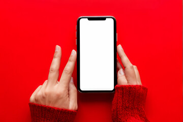 Mockup image of woman's hand holding mobile phone with white blank screen on bright red background: online shopping or online education concept, selective focus design 