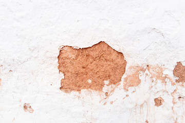 Close up of chipped plaster on white façade or wall with showing mud and straw of adobe style building in San Pedro de Atacama, Antofagasta, Chile in center of characteristic city in Atacama Desert