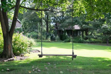 Empty swing set sits on a lush green lawn, inviting anyone to enjoy the simple pleasures of summer