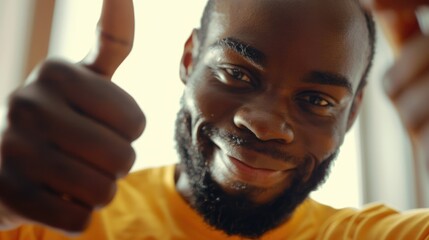 A man with a beard and a yellow shirt is giving a thumbs up