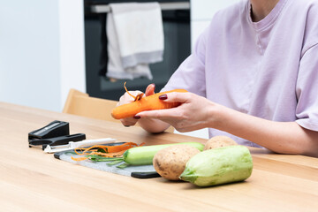 Close-up shot of a woman peeling vegetables using special vegetable peelers in the kitchen	
