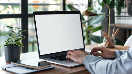 An image of a blank screen computer with a blank white background for advertising text and a handman using a laptop to look up information on a desk at home. A marketing and creative design mockup.
