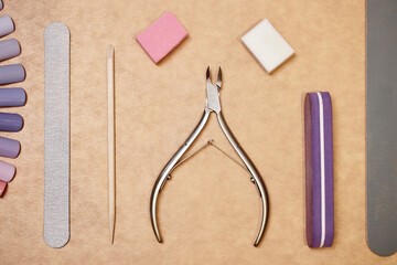 Flat lay shot of basic tools for nail care on beige background. Manicure at home set of nail files,...