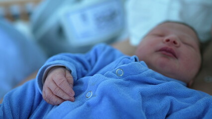 Close-up of a newborn baby sleeping peacefully in a blue outfit, showcasing the innocence and serenity of early life, highlighting the delicate features and calm demeanor of the infant