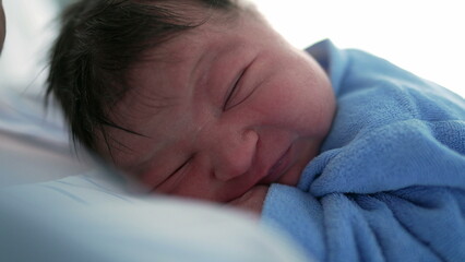 Side profile of a newborn baby in a blue onesie, gazing with curiosity and wonder, capturing the early moments of discovery and the innocence of a new life in a soft and serene setting