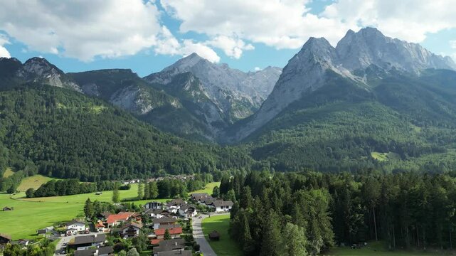 landscape near Garmisch-Partenkirchen Zugspitze mountain bavaria aerial panning shot summer sunshine wooden huts green grass