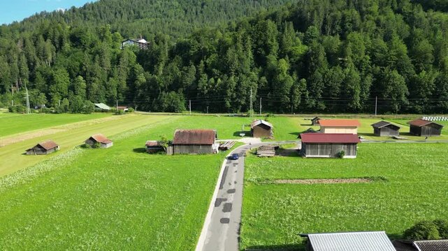 car driving on picturesque road near garmisch partenkirchen upward aerial drone wooden huts forest hill background