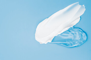 Gel and cream smears cosmetic texture on blue background with space for text
