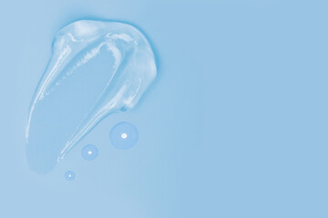 Gel smears and drops of cosmetic texture on blue background with space for text