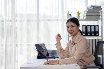 A woman is sitting at a desk with a laptop and a tablet