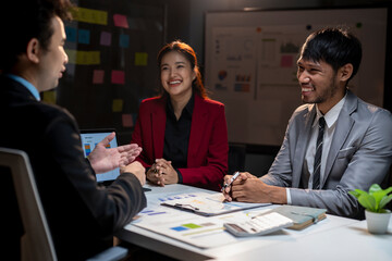 A group of people are sitting around a table, smiling and laughing