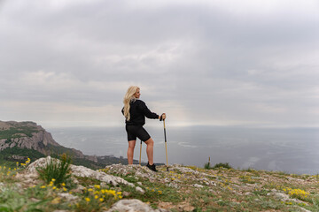 Obraz premium A woman stands on a hill overlooking the ocean