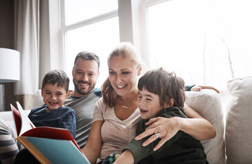 Fototapeta premium Parents, boy and children with book on sofa for smile, hug or learning with storytelling in family home. Mother, father and kids with reading, development or happy to relax for bonding, love and care