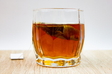 Brewing black tea bags in a glass. Natural, bagged flavored black tea on the table.