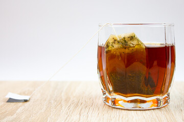 Brewing black tea bags in a glass. Natural, bagged flavored black tea on the table.