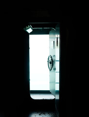 The door in old military war submarine warship ship is open to outside corridor , black background with copy space.Vertical.