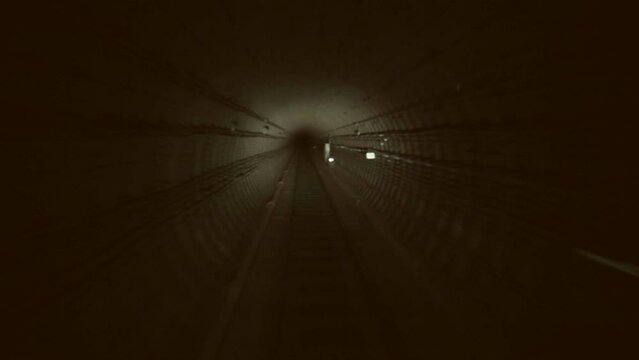 Subway train is going through the tunnel to the station. Dark underground tunnel.