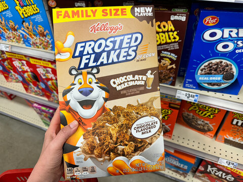 Temple, Texas - June 26, 2024: Hand holds a box of Kelloggs Frosted Flakes Chocolate Milkshake flavored cereal