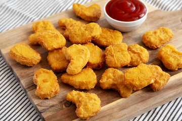 Crunchy Chicken Nuggets with Ketchup on a wooden board, side view.