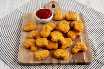 Crunchy Chicken Nuggets with Ketchup on a wooden board, side view.
