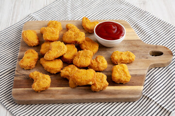 Crunchy Chicken Nuggets with Ketchup on a wooden board, side view.