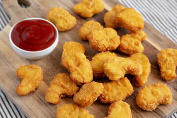 Crunchy Chicken Nuggets with Ketchup on a wooden board, side view.