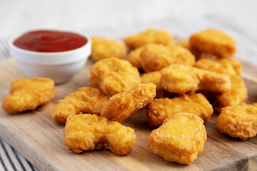 Crunchy Chicken Nuggets with Ketchup on a wooden board, side view.