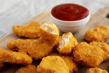 Crunchy Chicken Nuggets with Ketchup on a wooden board, side view. Close-up.
