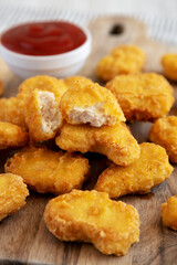 Crunchy Chicken Nuggets with Ketchup on a wooden board, side view. Close-up.