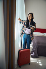 Smiling tourist contemplating cityscape upon arrival at her suite