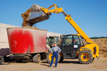 Worker woman control process unloading silage by tractor on farm, Fermented feed for food of cow. Compacting silo from harvest maize, preparing hay for winter © Parilov