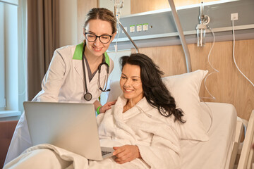 Smiling lady communicates online in a hospital room