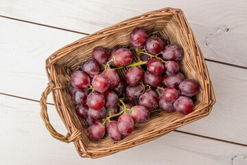 Ripe grapes in a basket on a wooden table, macro, top view.
