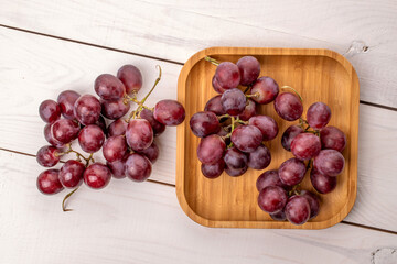 Ripe grapes with bamboo plate on wooden table, macro, top view.
