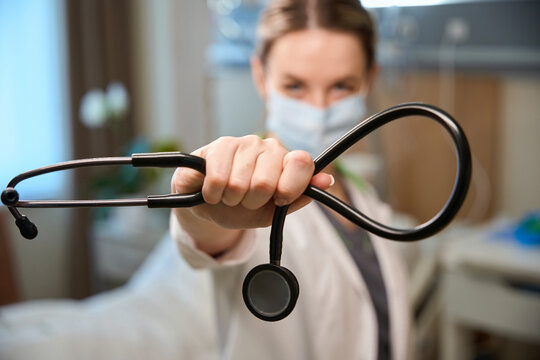 Lady in protective mask holds black statoscope in her hands