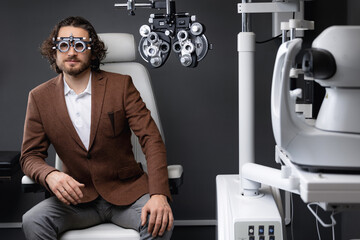 Ophthalmology clinic, adult man eyesight test with optometry machine. Selection of frames and...
