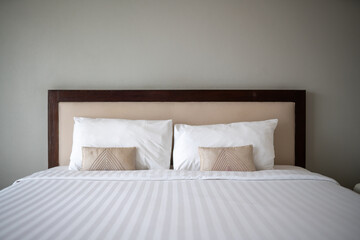 A bed with two pillows and a white sheet