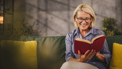 Mature senior woman sit in the living room and read a book