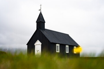 Stunning view of the black church of Budir with defocused grass in the foreground. Búðakirkja is a small wooden church located on the south side of Snæfellsnes, Iceland..