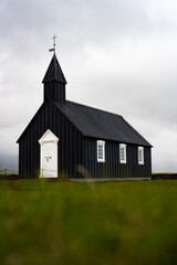 Stunning view of the black church of Budir with defocused grass in the foreground. Búðakirkja is a small wooden church located on the south side of Snæfellsnes, Iceland..