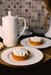 Lemon tart with zingy lemon curd topped with whipped lemon cream on white plate on wooden tray.